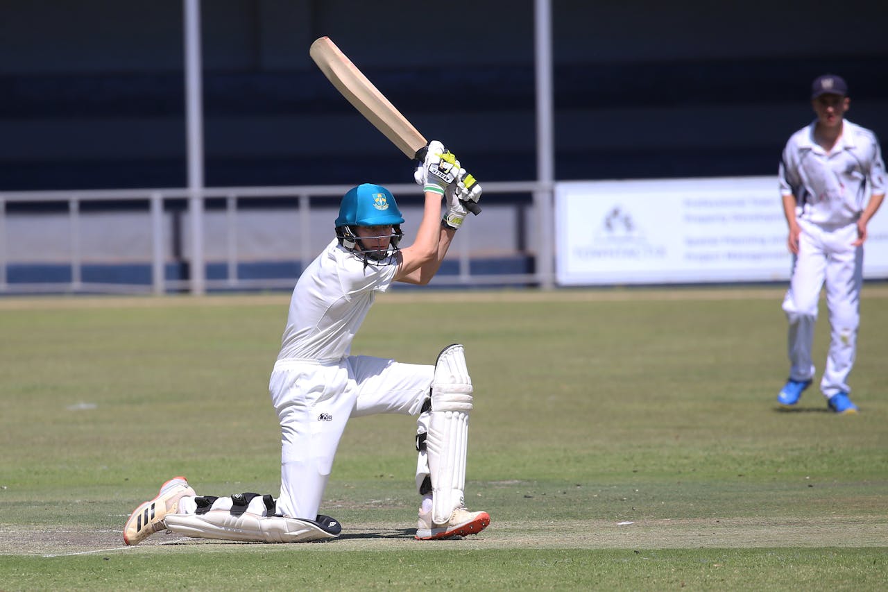Two young cricketers playing a match, showcasing batting skills on the field.