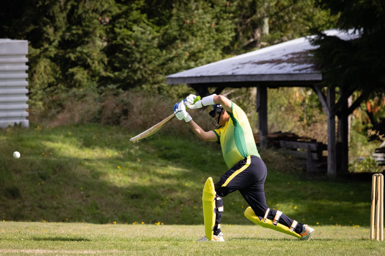 Cricketer batting during a match on a bright sunny day on a green field.