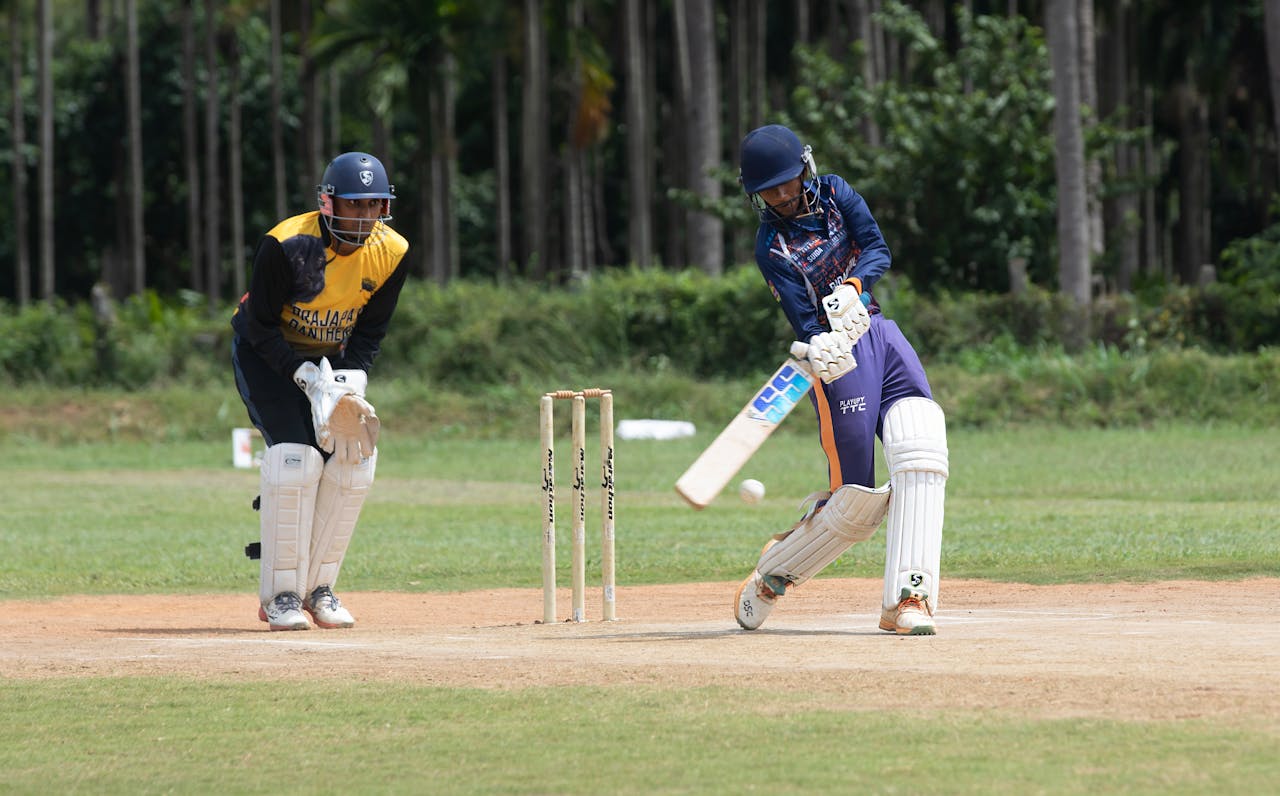 Two cricketers playing an intense match outdoors on a sunny day.